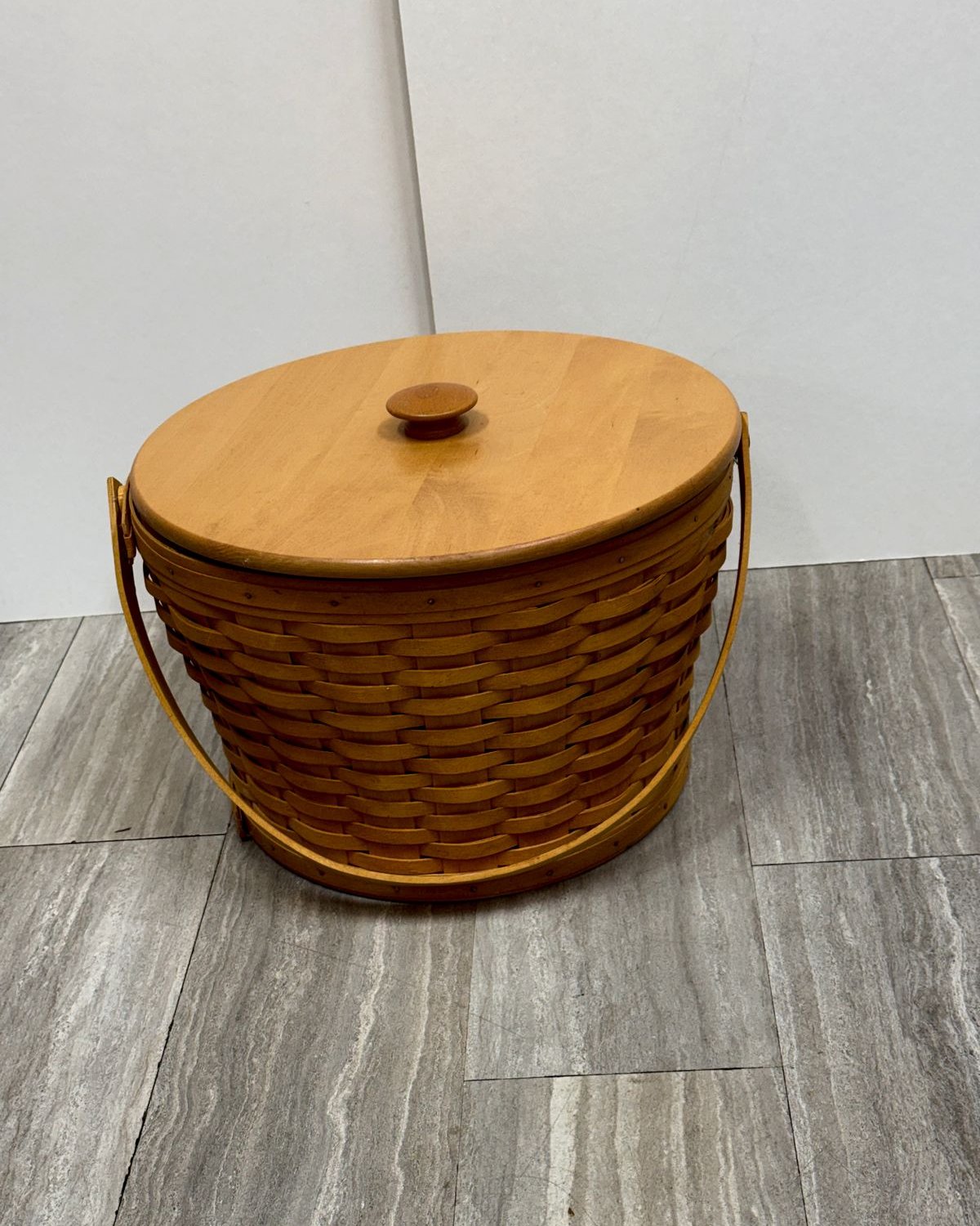 Vintage Longaberger handwoven maple basket with a round fitted wooden lid, turned knob, and a wooden swing handle.